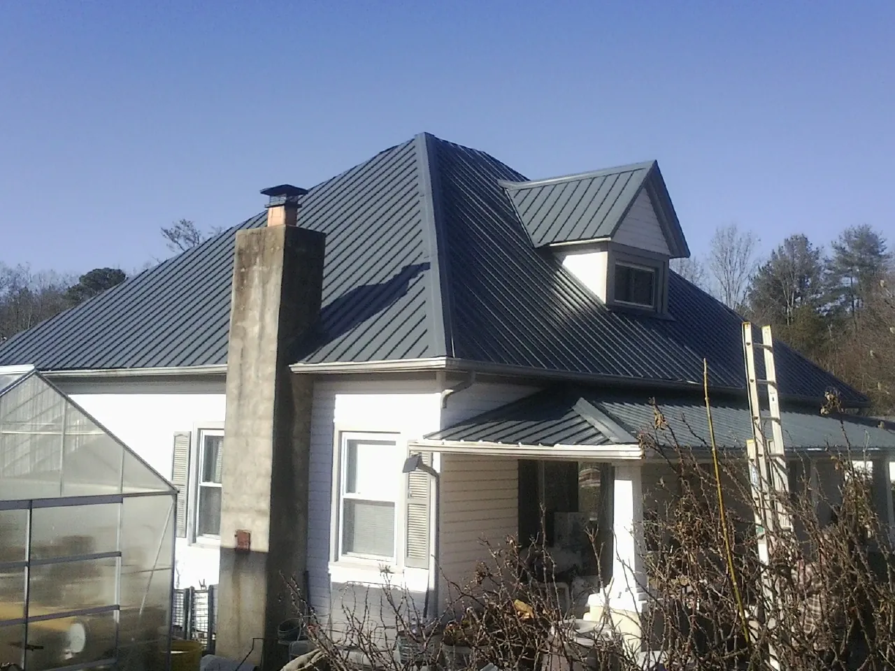 Dark blue standing seam metal roof on a white farmhouse with dormer — Slate & Tile Roof Repair by Roofing Brothers in Hawk Point