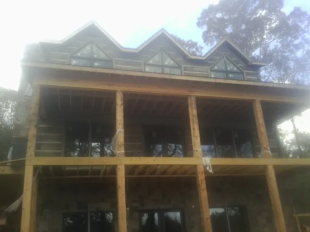 Dormers and porch framing on a large log home under construction — Roof Coating work by our crew in Hawk Point