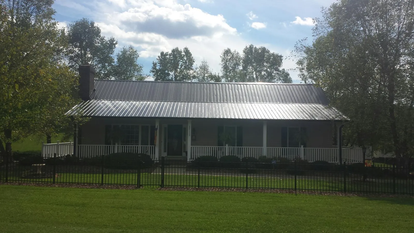 Gray metal roof on a brick ranch with a full width front porch — Gutter Guard Installation work by our crew in Hawk Point