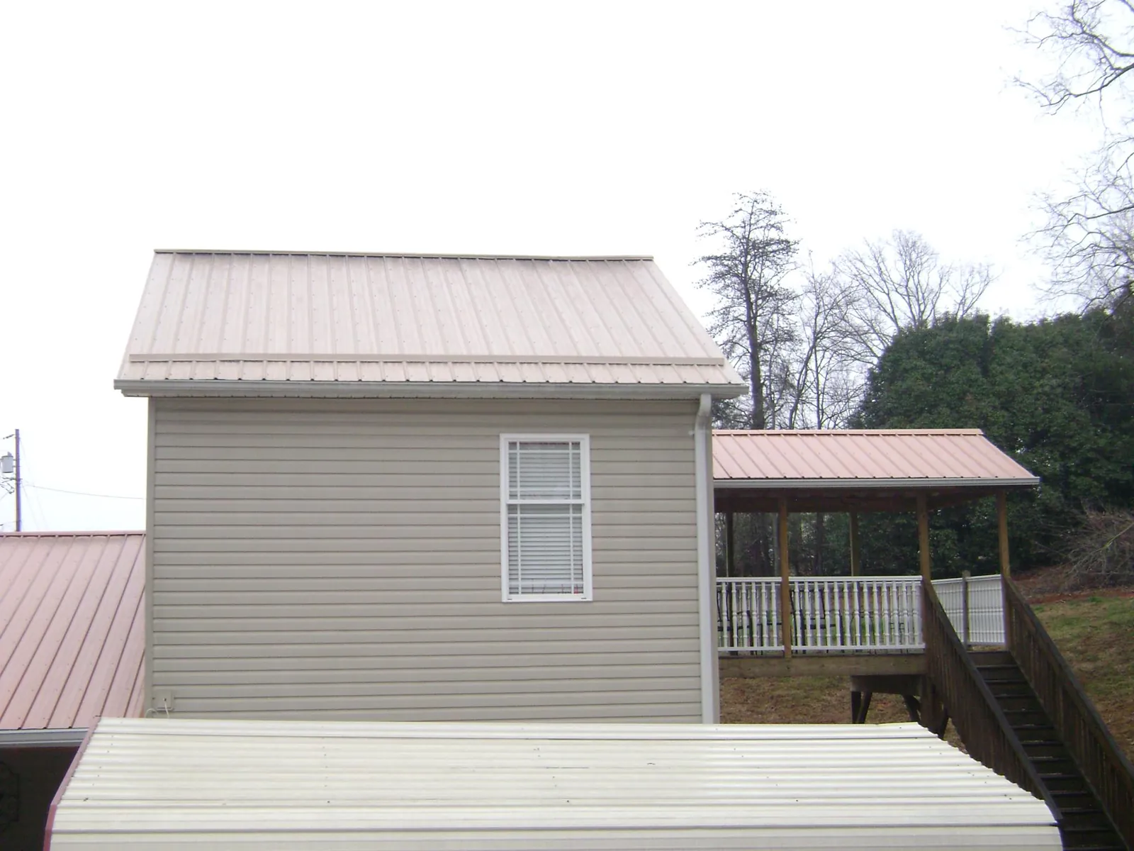 Tan metal roofs on a two story addition and attached porch, from a Roof Replacement job in Hawk Point